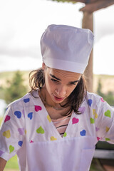 young woman dressed as a bakery making bread with flour eggs background green field with sun on vacations cordoba argentina