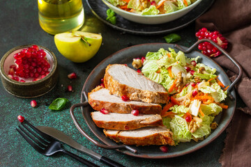 Healthly food. Baked meat steak salad and Chinese cabbage salad with apple, pomegranate, walnuts and on a stone table top.