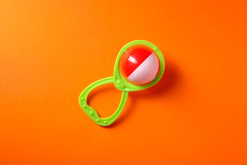 Baby rattle on orange background