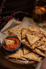 Baked cheese Tortilla chips with salsa dip sauce, homemade salty savory pastry snack for beer. Rustic wooden table, dark background with copy space.