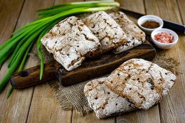 Homemade Finnish sandwich bread on a wooden table. Homemade bread and green onions on a dark background