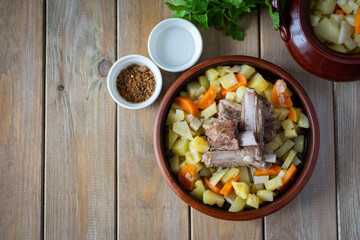 Baked potatoes with lamb ribs. Lamb with potatoes and vegetables on a clay plate
