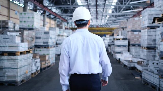 Follow footage of employees male warehouse worker engineer in hard hat working. walking through logistics center warehouse factory construction site logistics architect businessman man builder indoors