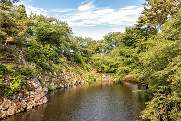 Fototapeta na wymiar The Moat and Old Stone Wall Surrounding Hirosaki Castle in Northern Japan