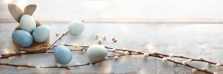 Tender blue easter eggs decorated with pussy willow on gray vintage planks. Horizontal spring background for easter greetings.