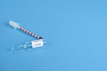 Obraz premium Glass vaccine and syringe for vaccination against the COVID-19, SARS-CoV-2 coronavirus pandemic on blue background