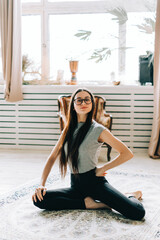 Obraz na płótnie Canvas Portrait of cheerful brunette fitness woman doing yoga indoors at home. Staying fit and healthy