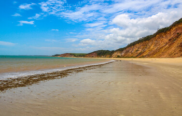 Praia com água cristalina e nuvens no céu