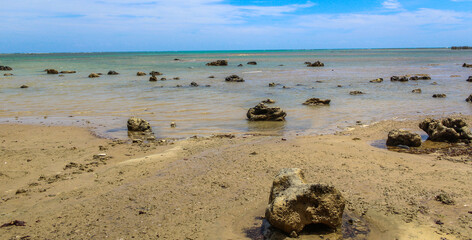 Praia com água cristalina e pedras no mar
