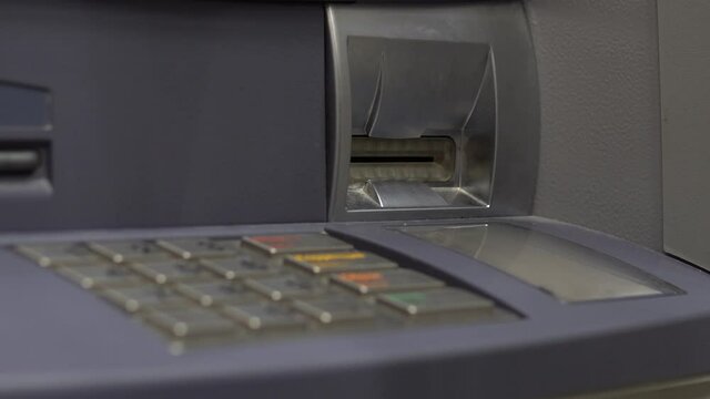 A young woman inserts a bank card into an ATM. ATM for cash withdrawal and deposit. Woman's hand close-up.