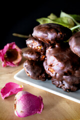 
Delicious oatmeal cookies, roasted apple and melted dark chocolate on dark table and colorful fresh flowers