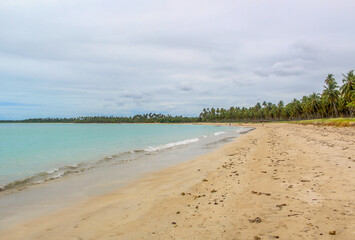 Praia com água cristalina e nuvens no céu