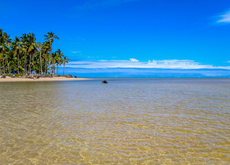 Praia com &aacute;gua cristalina e nuvens no c&eacute;u