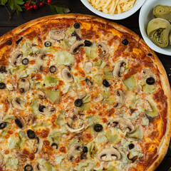 Just made fresh pizza with artichoke and olive, vegetarian meal with organic products. Fast food for lunch, ingredients on the background. Italian pizza recipe.