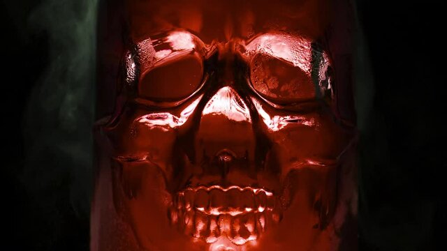 Alchemical Experiments in a Glass Skull. Bright, rich blood-red glass vessel in the form of the skull, from which are evaporation and slow down the edges on a black background