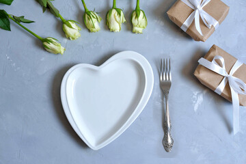 empty white plate with hearts on Ultimate Gray background with white roses and fork. The moment of a wedding, anniversary, engagement, or Valentine's Day. Happy day.