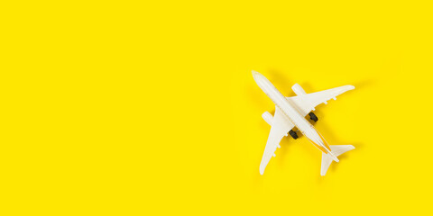 Plane model and face mask on a yellow background. Flight impact of coronavirus (COVID-19) concept.