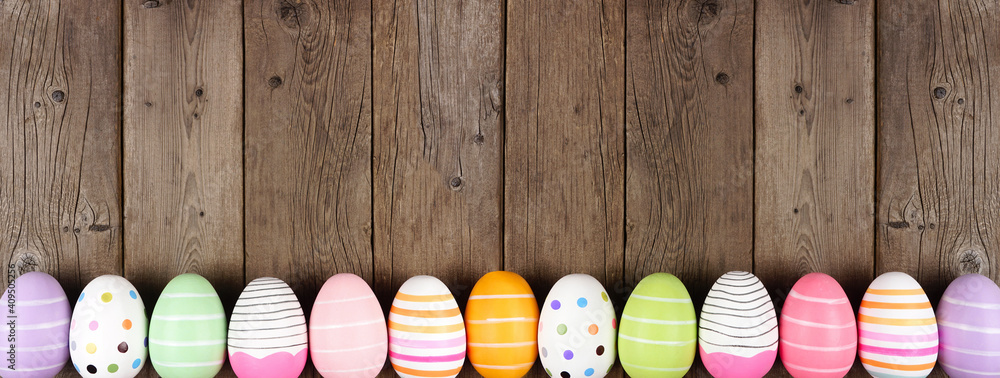 Poster colorful easter egg long bottom border. top down view against a rustic wood banner background. copy 