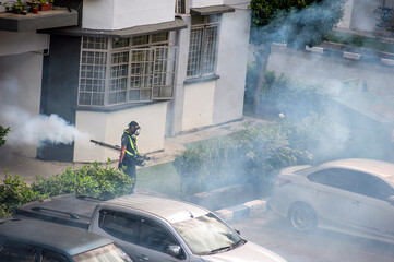 Healthcare worker using Fogging machine spraying chemical to eliminate mosquitoes and kill larvae to fight against the spread of dengue fever, Zika virus or Malaria at a residential area.