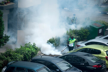 Healthcare worker using Fogging machine spraying chemical to eliminate mosquitoes and kill larvae to fight against the spread of dengue fever, Zika virus or Malaria at a residential area.