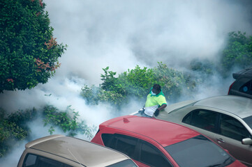 Healthcare worker using Fogging machine spraying chemical to eliminate mosquitoes and kill larvae to fight against the spread of dengue fever, Zika virus or Malaria at a residential area.