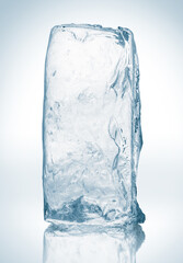 Crystal clear, pure ice block, on white surface with reflection. Big piece of ice.