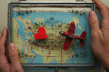 travel concept with map background, rustic aircraft and red heart