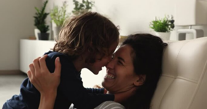 Close up young mother communicate with preschool son, family play sit on chair at home talking laughing touch noses enjoy priceless time together. Happy motherhood, babysitting work, adoption concept