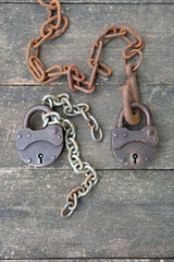 Two old rusty padlock and rusty chain on wooden background . High quality photo
