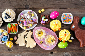 Fototapeta na wymiar Easter table scene with a selection of desserts and sweets. Top view table scene over a wood background. Spring holiday food concept.