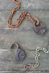 Two old rusty padlock and rusty chain on wooden background in steampunk style. High quality photo