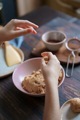 Child hands making sweet balls cookies called Potato of marzipan, biscuits, cocoa. Process of dessert cooking, wooden table with ingredients. Selective focus, copy space