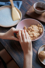 Child hands making sweet balls cookies called Potato of marzipan, biscuits, cocoa. Process of dessert cooking, wooden table with ingredients. Selective focus, copy space