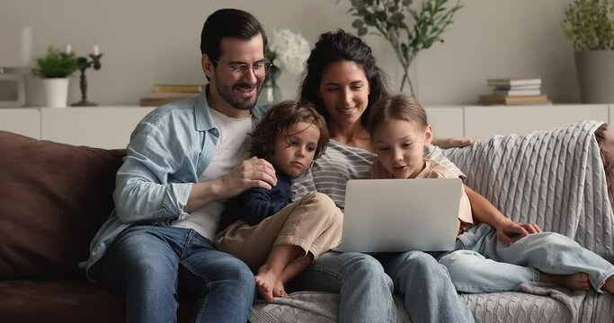 In living room children their mom and dad spend time together having fun on internet use laptop watch cartoons, parents buy goods for kids online. Parental control, ecommerce clients family concept