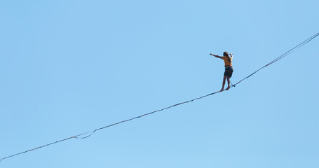 A man walks along the highline against the blue sky.
