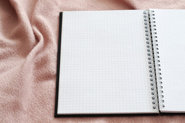 empty opened notebook with spiral on pink blanket