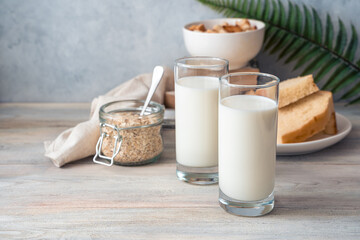 Milk breakfast, two glasses of milk, oatmeal and breadcrumbs on a gray background. Side view with copy space. The concept of proper nutrition.