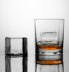 Glass of scotch whiskey and ice on a light background.
