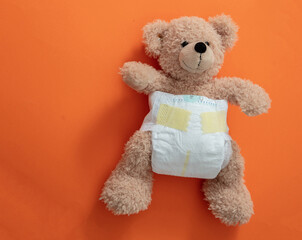 Teddy with a baby diaper on orange color background.
