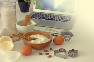  Ingredients for baking and a laptop on the table in the kitchen
