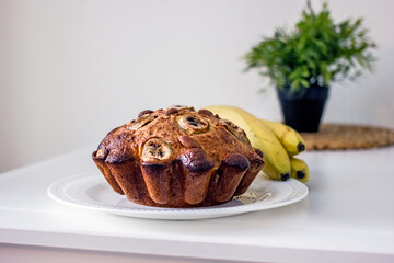 Homemade gluten free cake made from alternative flours, sugar free with banana and nuts on a white plate on a white table. Homemade baked goods and natural ingredients, healthy food, Home hobbies 