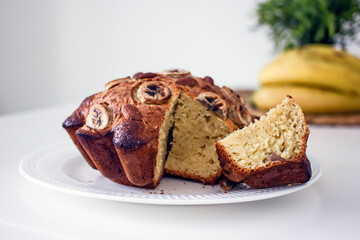 Homemade gluten free cake made from alternative flours, sugar free with banana and nuts on a white plate on a white table. Homemade baked goods and natural ingredients, healthy food, Home hobbies 