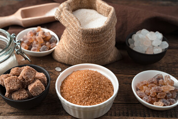 Cane sugar, refined sugar, white and lollipop sugar on a wooden background. Side view, Culinary background. The concept of food products.