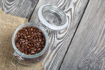 Coffee beans. Poured into a pull-lock jar. Stands on linen and pine planks. Shot from above