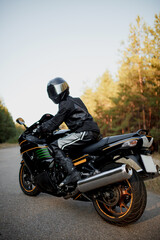 Rider on a motorbike driving at sunset - space for your text, biker and motorbike ready to ride