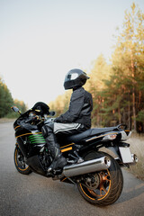 Fototapeta na wymiar Handsome motorcyclist wear leather jacket and holding helmet on the road