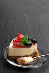 Slice of creamy cheesecake with jellied berries on top on stone background