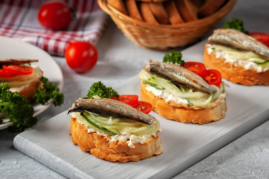 Smoked sprat sandwich - fish, fresh cucumber and tomato. Sprat sandwiches on toasted slices of bread