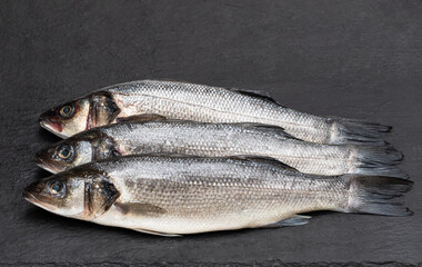 Raw whole seabass fish on stone background