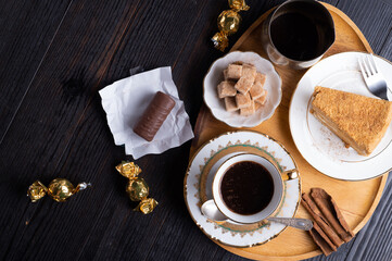 coffee with dessert served at wooden tray at black wooden table. flat lay